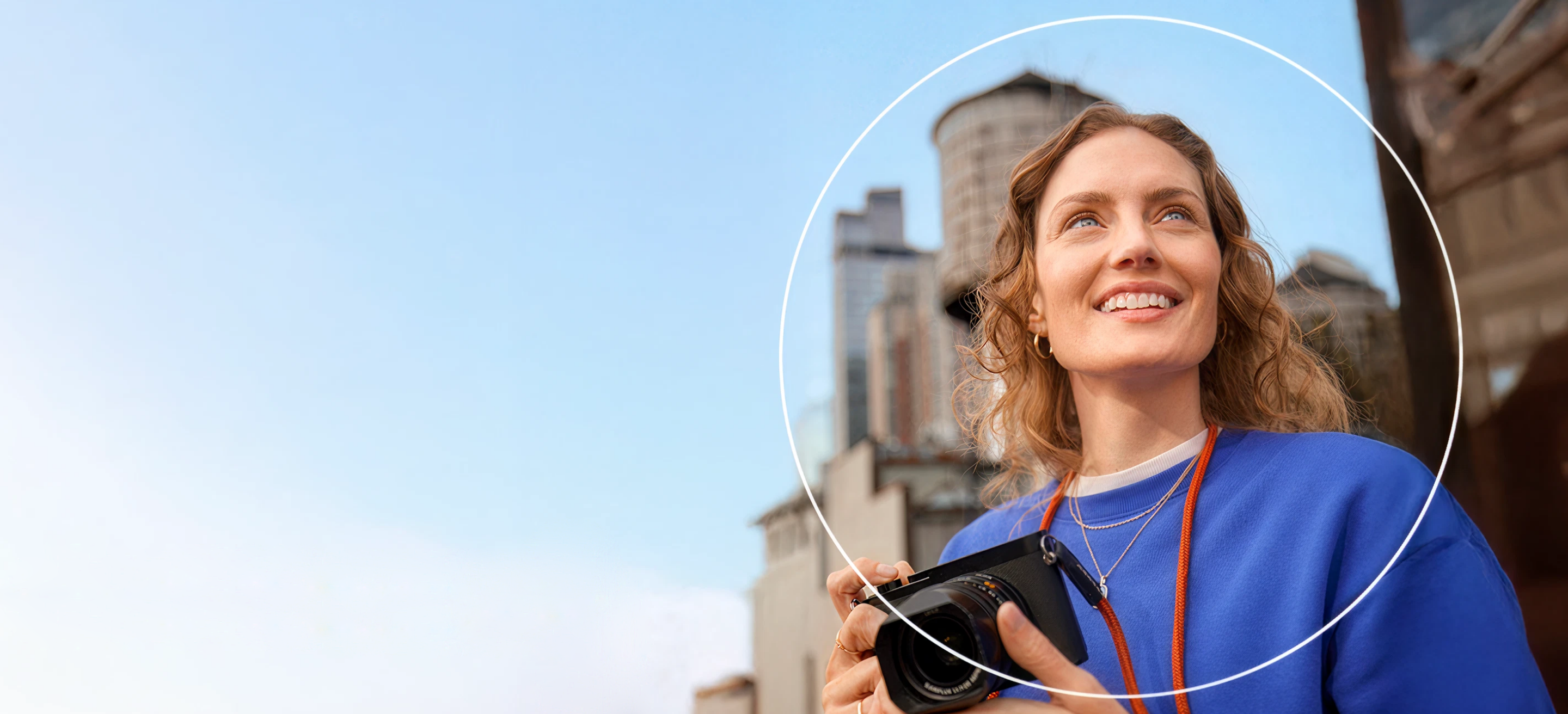 Woman outside holding a camera and looking off into the distance with a white circle around her.
