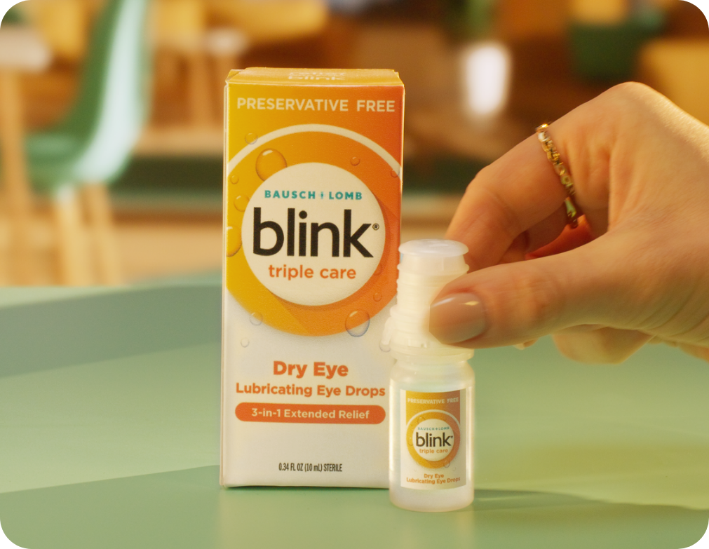 Blink Triple Care eye drops packaging next to a hand holding the bottle.
